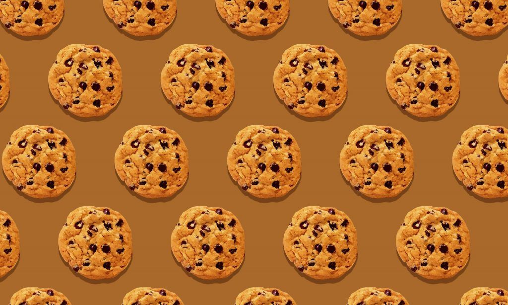 A pattern of chocolate chip cookies on a brown background.